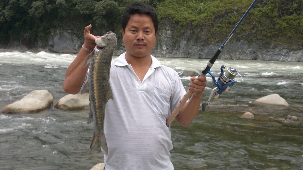 Angler with catch beside a flowing river