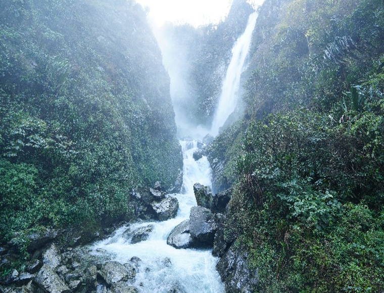 Mompani Waterfall cascading through a green gorge
