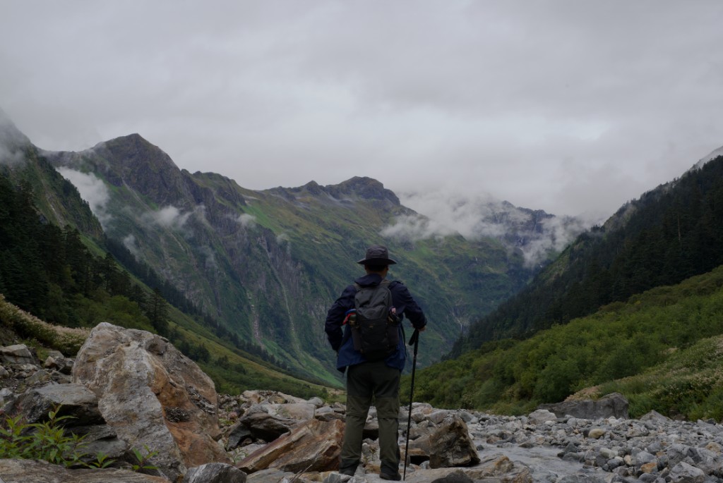Trekker by a stream in high-altitude valley